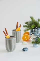 Christmas mulled wine. Punch, grog. Next to it are Christmas toys and fir branches in a glass vase on a light background.
