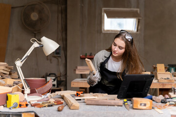 Portrait of a female carpenter looking at designs on a laptop for making her furniture in a...