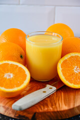 Orange Juice drink with whole and sliced Oranges on wooden cutting board