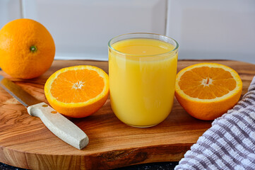 Orange Juice drink with whole and sliced Oranges on wooden cutting board