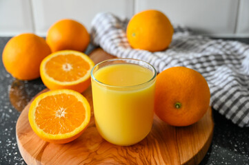Orange Juice drink with whole and sliced Oranges on wooden cutting board