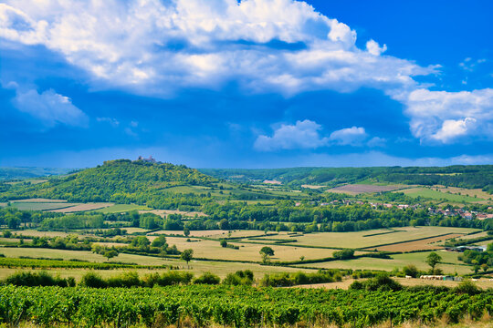 The hill of V&eacute;zelay, department of Yonne, Morvan, Burgundy, France. Surrounded by small-scale farm country, trees and vineyards. Sunny, with rising thunderclouds.
