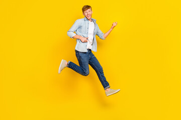 Fototapeta na wymiar Full length photo of handsome guy red hair blue shirt jeans sneakers fooling playing imaginary guitar isolated on yellow color background