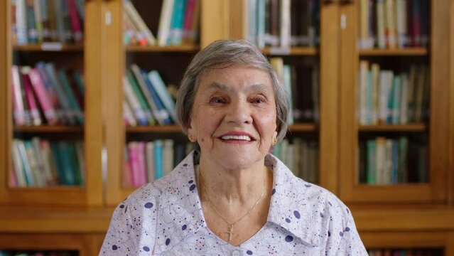 Senior woman, laughing or happy in house library, home interior or book room. Portrait of smile, comic or face of elderly pensioner in retirement with teeth showing on background with education books