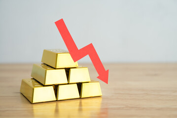 Gold bars stacks and red graph chart falling down on wooden background copy space. Gold price decrease in commodity trading bear market investment concept. Gold is store of value in recession crisis?