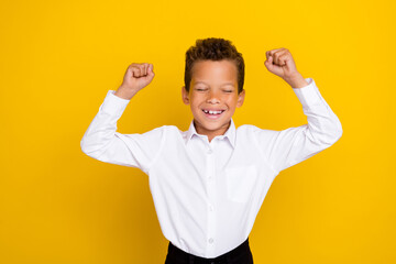 Fototapeta premium Photo of overjoied cheerful boy raise hand fist rejoice win contest competition eye closed isolated on yellow color background