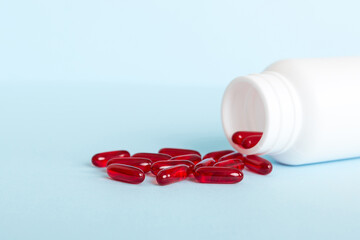 Red pills spilled around a pill bottle. Medicines and prescription pills flat lay background. Red medical capsules