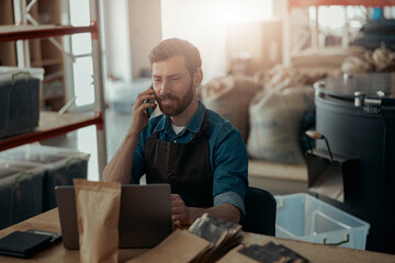 Handsome man make business talking phone on own small coffee factory