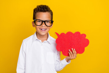 Photo of pretty positive stylish boy schoolkid hand hold bright paper bubble card stand empty space isolated on yellow color background