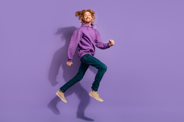 Full size photo of crazy beard red hair guy run wear sweatshirt jeans sneakers isolated on violet background