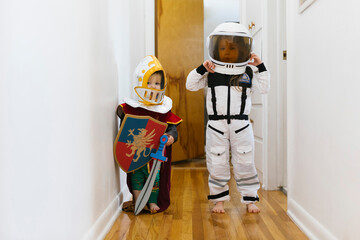 Toddler boy (2-3) in knight costume and girl (2-3) in astronaut costume playing at home