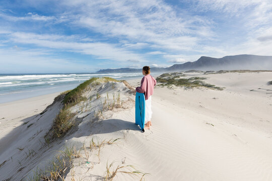 South Africa, Western Cape, Hermanus, Teenage girl (16-17) preparing to surf down sand dunes in Walker Bay Nature Reserve