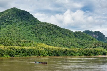 Long Boat travels down the Mekong River at Luang Prabang, beatiful river beetwen mountain forest