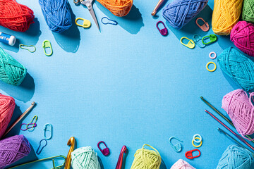 Crochet background with assorted colorful yarn and knit accessories over blue, top view, flat lay...