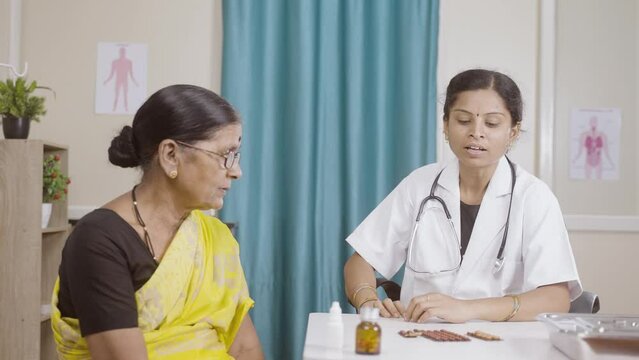 senior indian docter sugesting healthy tips or counsulting patient at hospital - concept of healthcare, professional occupation and mental illness therapy.