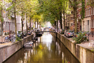 canal humilde y estrecho con puente pequeño en amsterdam, paises bajos