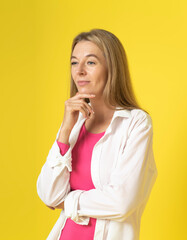 Portrait of attractive minded woman touch hand chin look copyspace think thoughts wearing white shirt isolated over yellow color background. Thoughtful charming woman thinking and looking away