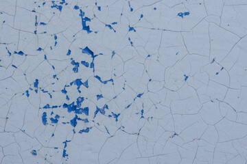 Blue peeling paint on the wall. Old concrete wall with cracked flaking paint. Weathered rough painted surface with patterns of cracks and peeling. High resolution texture for background and design.