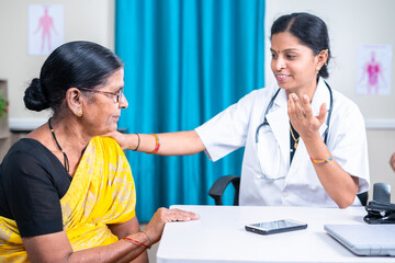 senior indian docter sugesting healthy tips or counsulting patient at hospital - concept of...