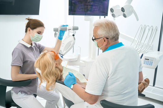 Woman on dental chair getting teeth whitening in clinic