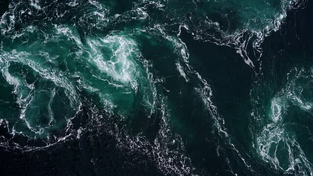 4K drone video with birds-eye view of the abstract and powerful water currents, rapids and whirlpools of the worlds larges maelstrom Saltstraumen, Norway.