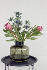 south african Protea flower and Eryngium flower bouquet in vase on table  