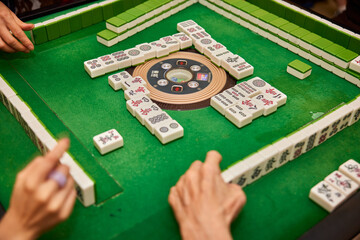 Elderly people playing mahjong, indoor gamble activity at home during spring festival.