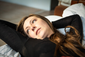 Fototapeta premium Relaxed portrait of an attrractive woman, lying on her sofa