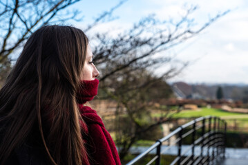 Attractive thirty year old woman looking in the distance in a city park during winter