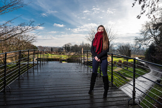 Portrait of a strong thirty year old woman, wearing winter clothes , standing on a pedestrian bridge in a park in winter