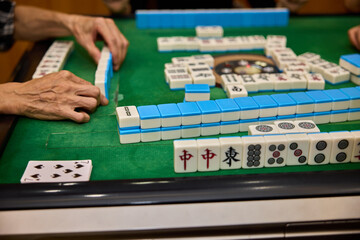 Elderly people playing mahjong, indoor gamble activity at home during spring festival.