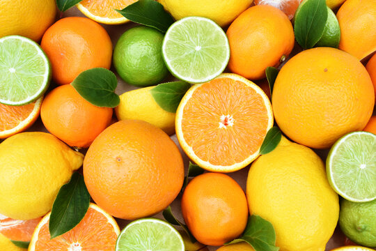 Colorful bright background of fresh ripe sweet citrus fruits: orange and tangerine, green lime and yellow lemon