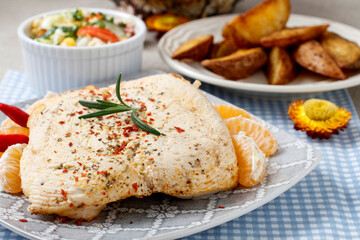Meat with herbs and baked potatoes in the background.