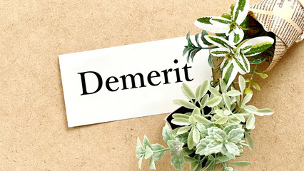 コルクボードの上の白い用紙にDemerit文字と植物_ワイド