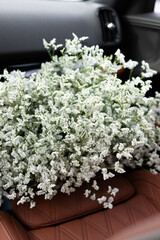 Bouquet of white Limonium Sinensis flowers on the leather car seat
