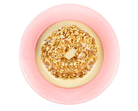 Glazed Donut Topped With Chopped Peanuts On A Pink Plate. Isolated.