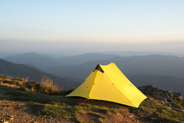 Yellow tent against the backdrop of an incredible mountain landscape during morning sunrise. Amazing highland. Tourism concept © Ivan Kmit