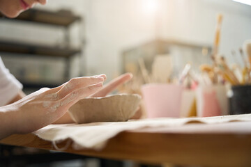 Student diligently sculpts edges of clay plate with her fingers