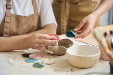 Women hold samples of paint for clay products in their hands