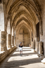Fototapeta na wymiar Béziers Cathedral or.Cathédrale Saint-Nazaire-et-Saint-Celse de Béziers, Hérault, Occitanie, South France. Woman in a internal corridor looking to the cross