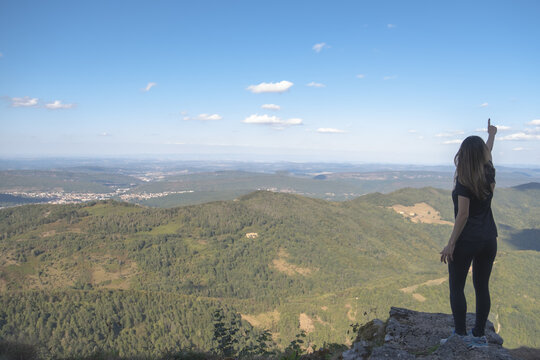 Young woman pointing to the horizon from the ruines of the Montsegur castle in France. Achievement concept