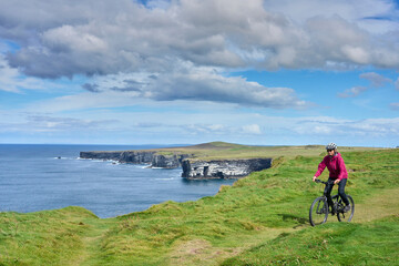 nice senior woman on mountain bike, cycling on the cliffs of Cnoc an Daimh, Kilgalligan the northern part of the Republic of Ireland