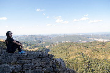 Naklejka premium Young Woman with sunglasses seated at the top of the ruines of the Montsegur castle in France