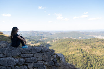 Naklejka na ściany i meble Young woman seated and looking to the horizon from the ruines of the Montsegur castle in France