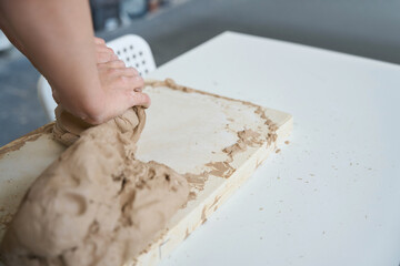 Craftswoman works with a piece of clay on a board