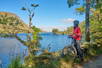 nice senior woman on mountain bike, cycling at Lough Beagh in the Glenveagh National park, near...