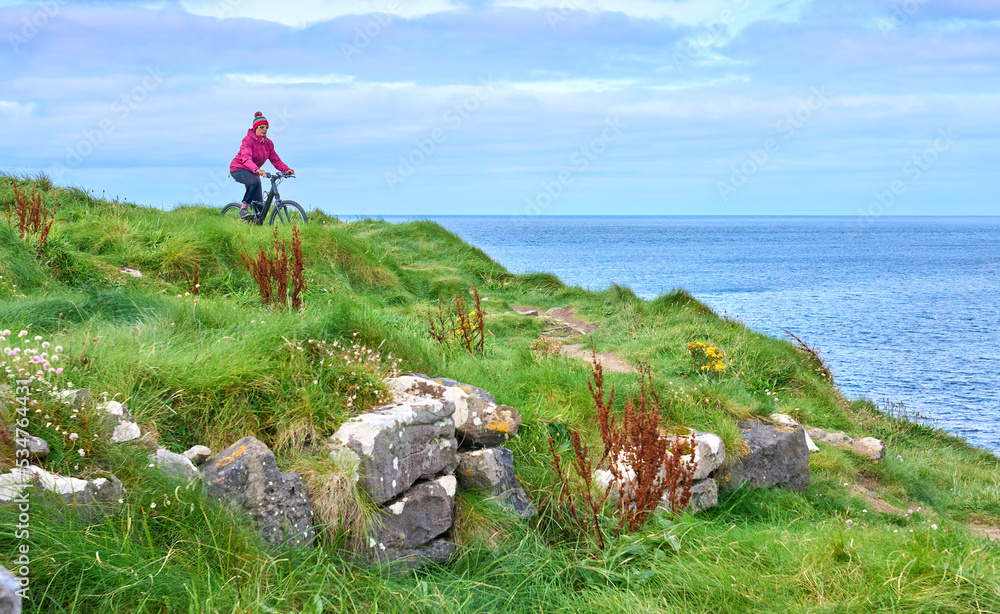 Wall mural nice senior woman on mountain bike, cycling on the cliffs of cnoc an daimh, kilgalligan the northern