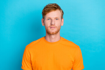 Photo of handsome positive serious man with ginger hairdo dressed orange t-shirt looking at camera...