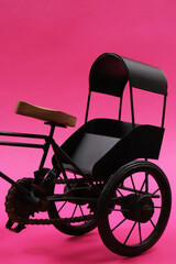 Fototapeta na wymiar Decorative souvenir bike. Vintage three-wheeled cart on a pink background. Shallow depth of field