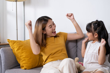 Asian mother and daughter embrace and playing together with happiness and smile inside of living room. Mom and children relationship positive emotion with copy space for text.
